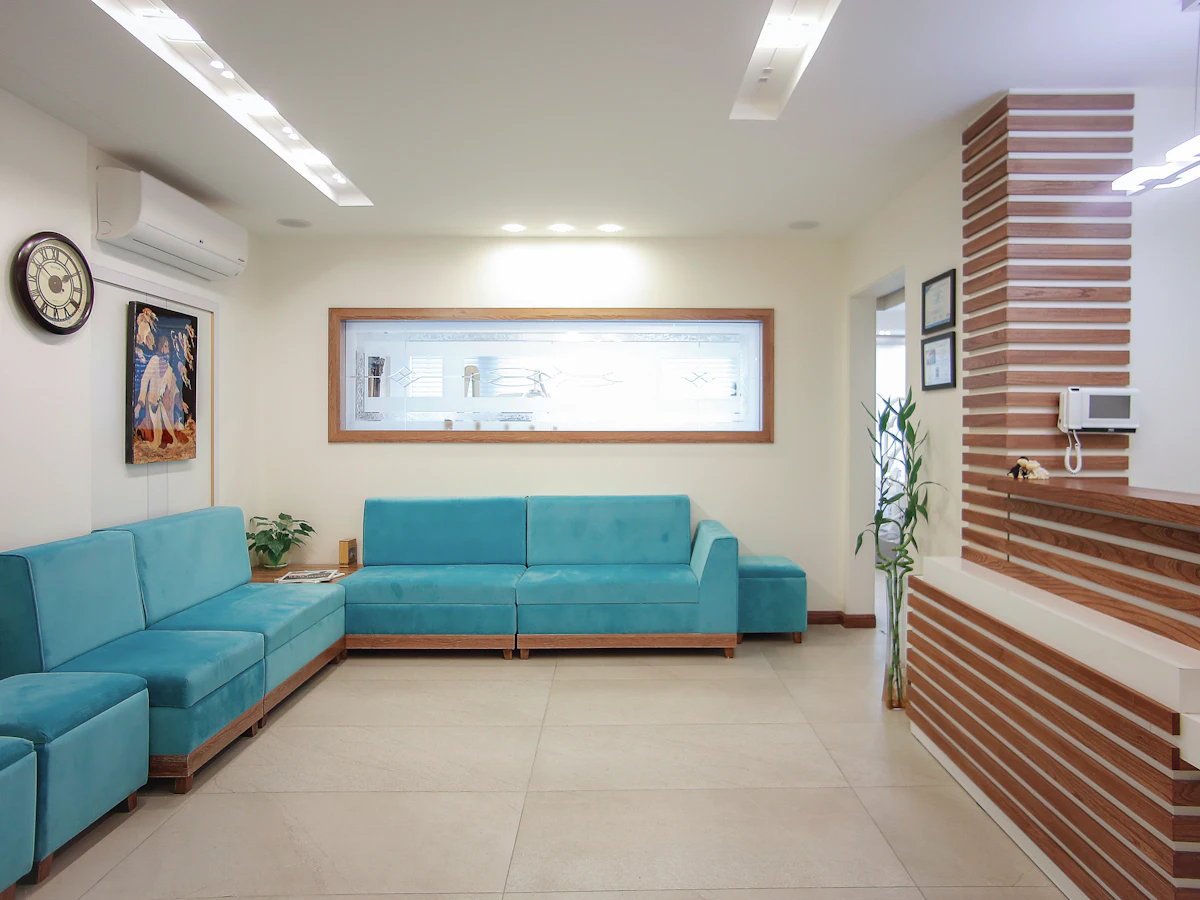 Sala de espera luminosa con sillones turquesa y una planta